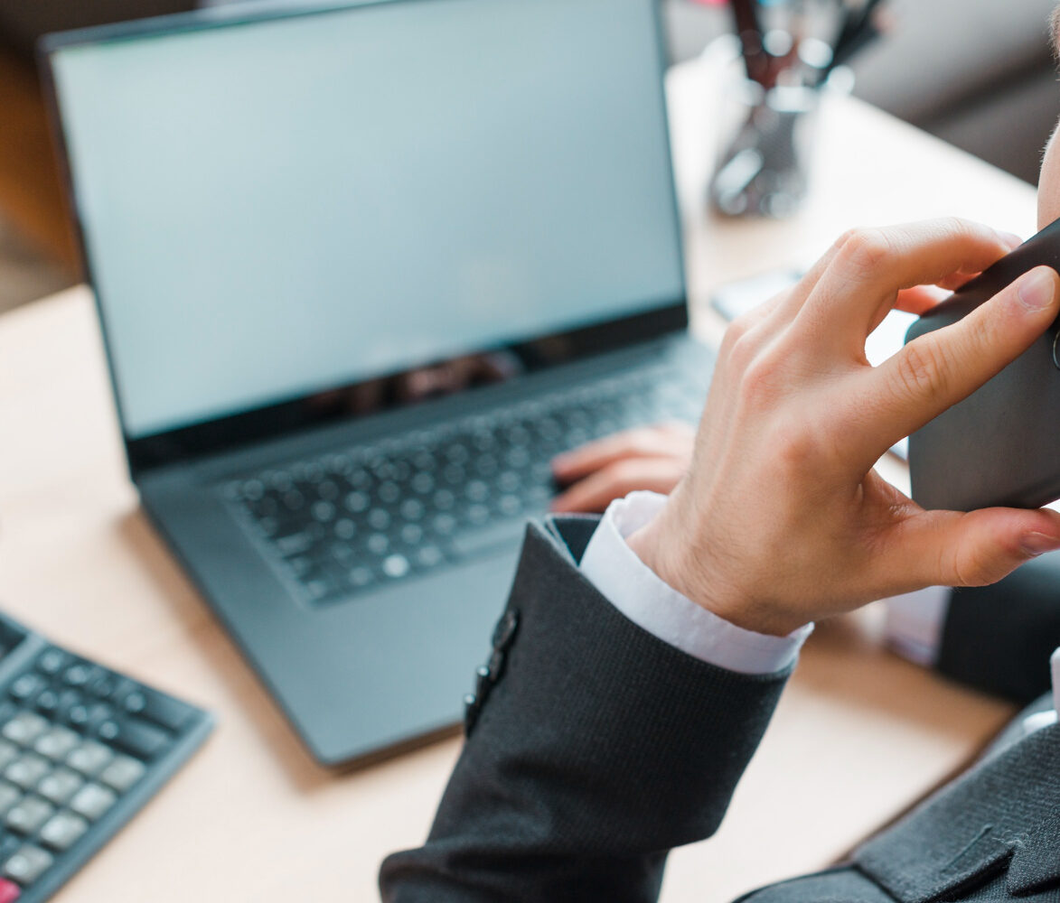 Daniel Bousquet en costume à Toulouse, travaillant au bureau sur smartphone et ordinateur portable,